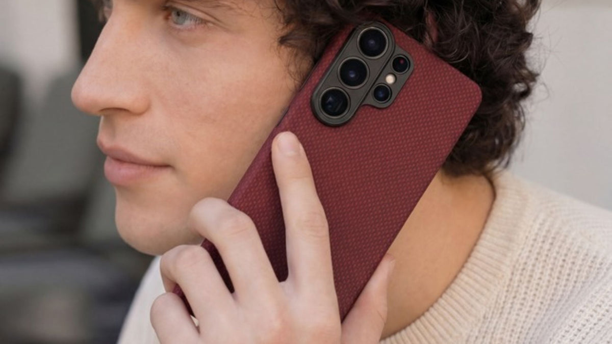 Guy with curly hair holding Galaxy S26 Ultra in red Thinborne case near his ear
