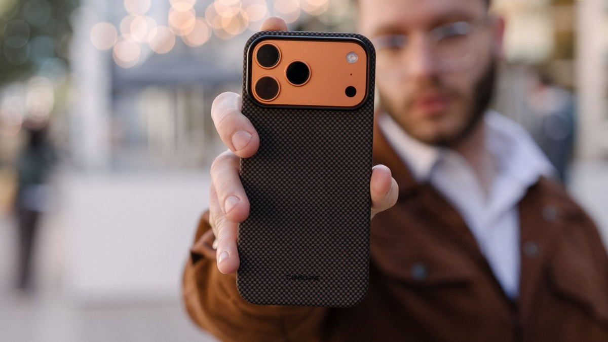 Guy in brown jacket holding up iPhone 17 Pro Max in black Thinborne case