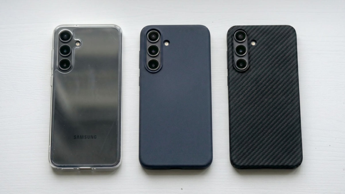 The Galaxy S26 phones side by side in different cases - plastic, silicone, and aramid fiber on gray background