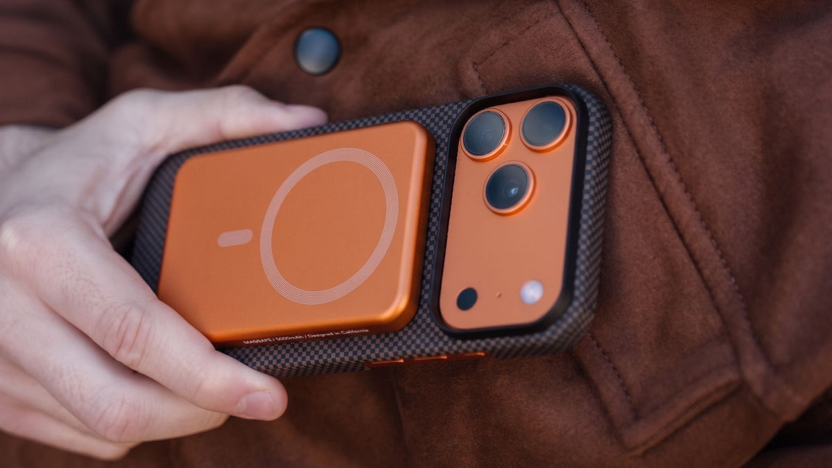 Man’s hand holding iPhone 17 Pro Max in black aramid fiber Thinborne case near brown jacket