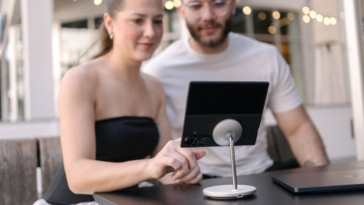 Man and woman facing Galaxy Z Fold 7 in black Thinborne case while attached to a MagSafe stand