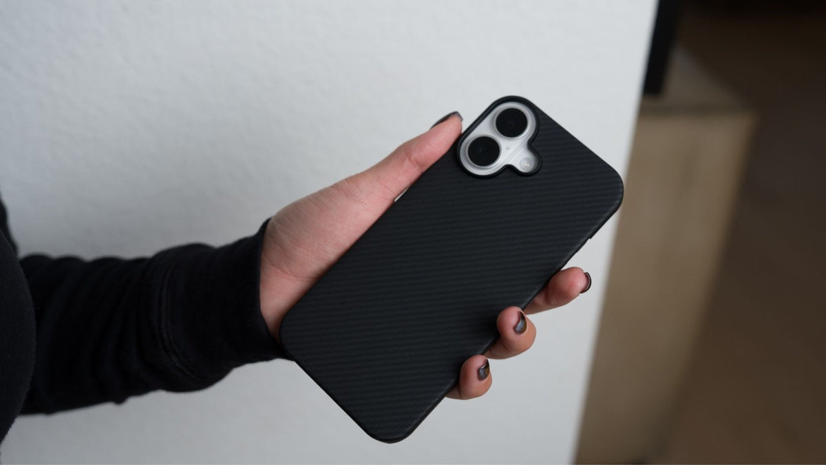 A woman’s hand holding an iPhone 17 in a black Thinborne aramid fiber case