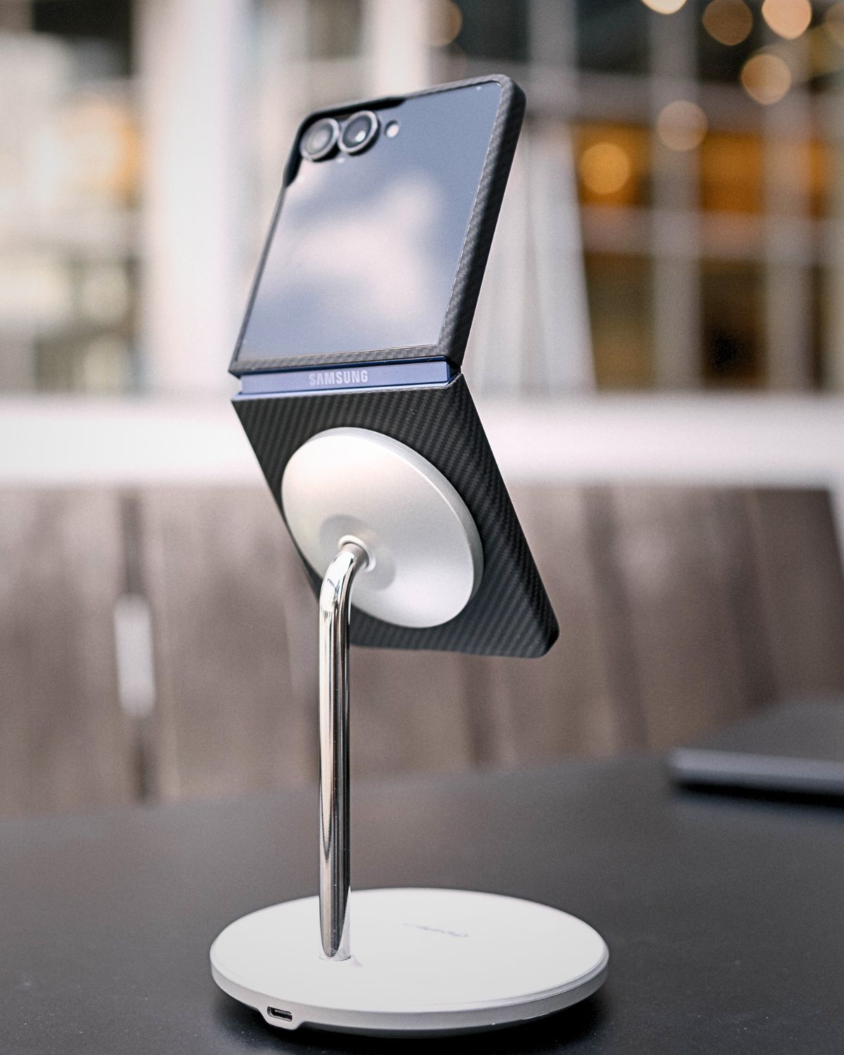  A half-folded Z Flip 7 with a carbon fiber case on a magnetic stand.