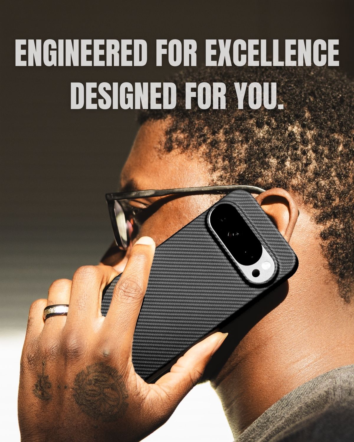 A close-up side view of a man on a call, holding a Google Pixel 10 pro 
in a black carbon fiber case.
