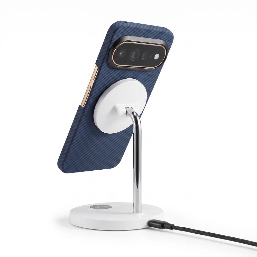 A dark blue carbon-fiber pixel 11 pro xl phone case on a smartphone, displayed on a white magnetic charging stand with a silver metal arm and a black charging cable, against a white background.