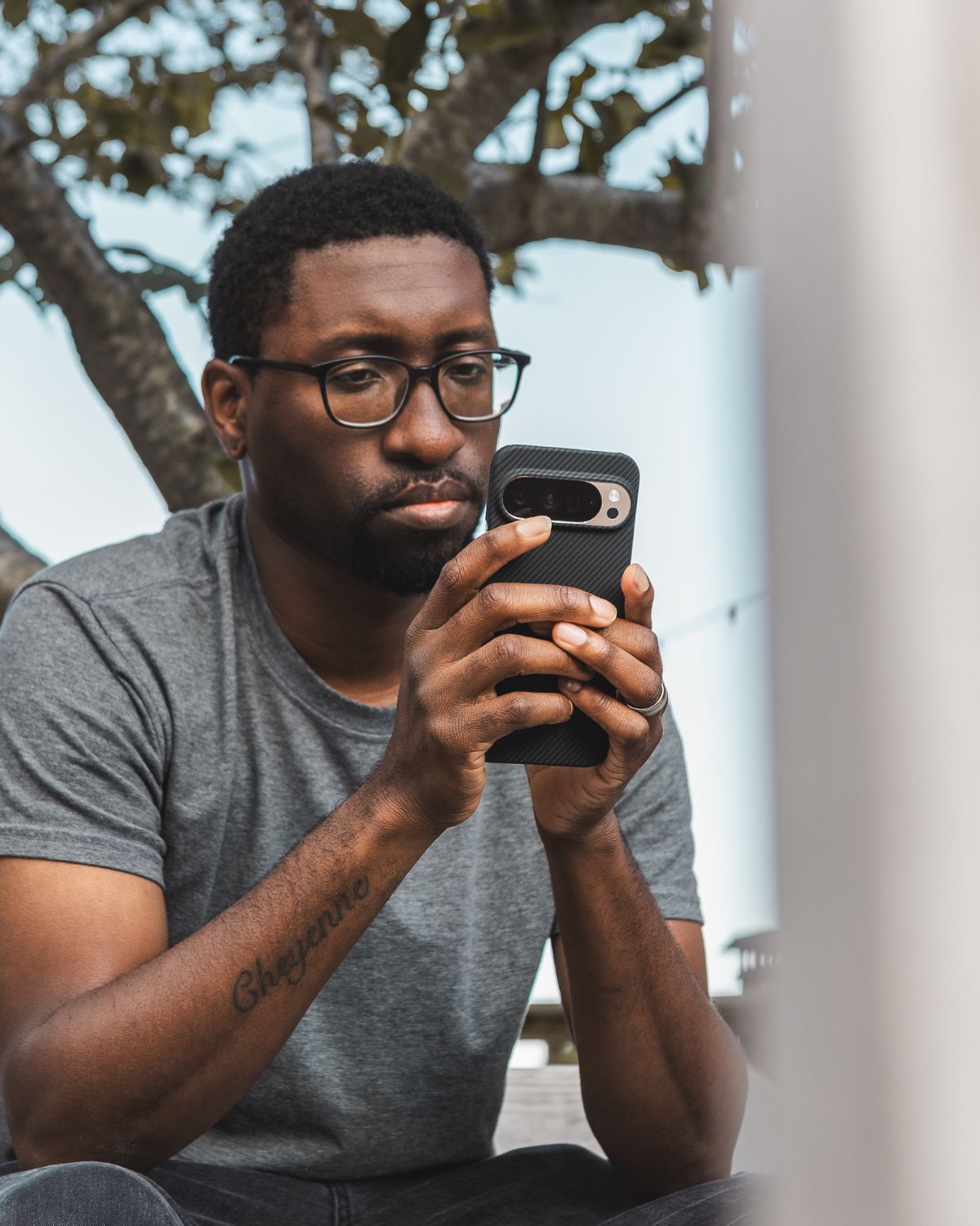  A man with glasses looks intently at his phone, held in both hands. The phone is in a black, textured Pixel 10 Pro xl case.