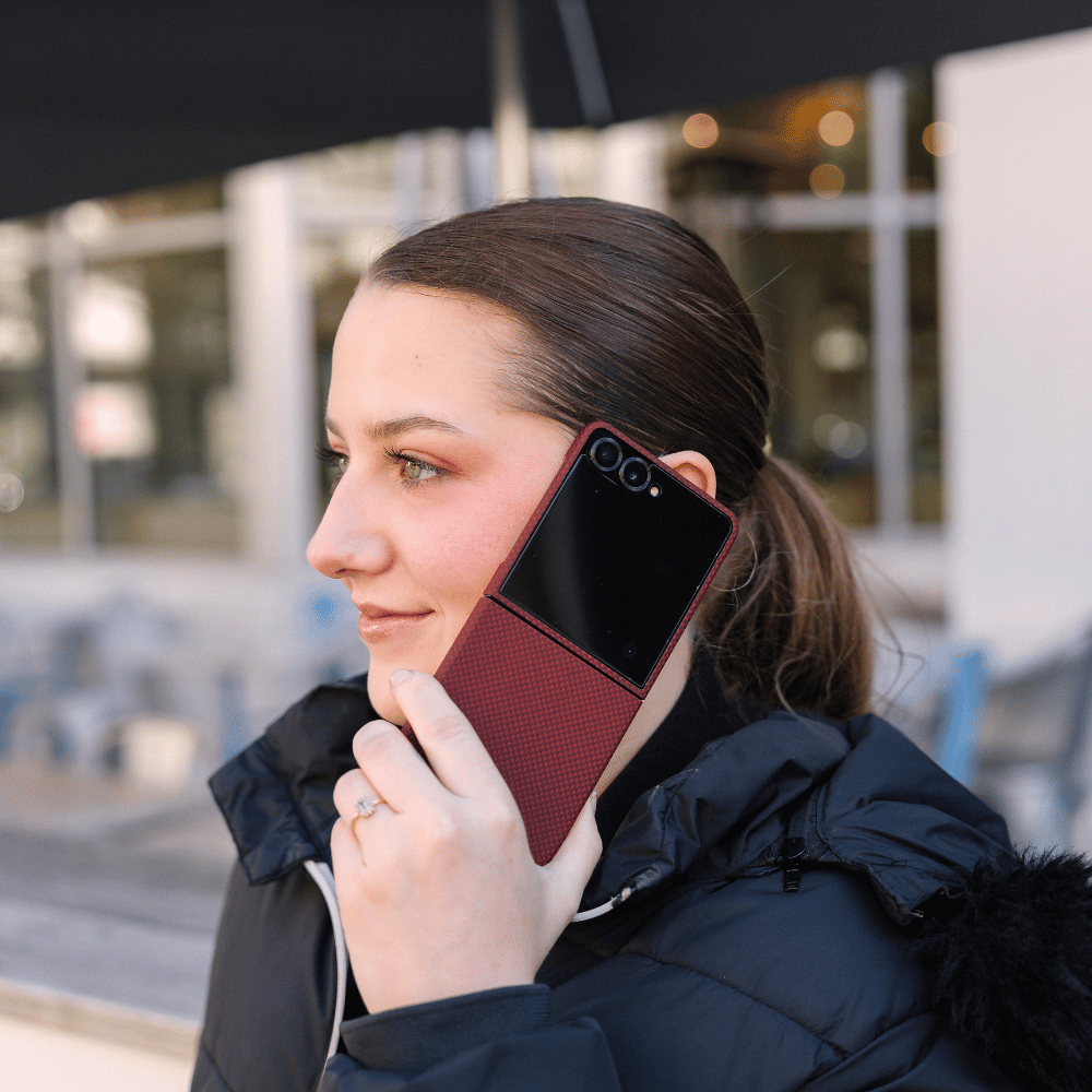Woman making a call with a Samsung Galaxy Z Flip 8 protected by an ultra-thin red woven aramid fiber case.