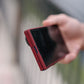 A hand holding a folded phone to showcase the front cover screen and the slim red bezel of the aramid fiber galaxy z fold 8 ultra case