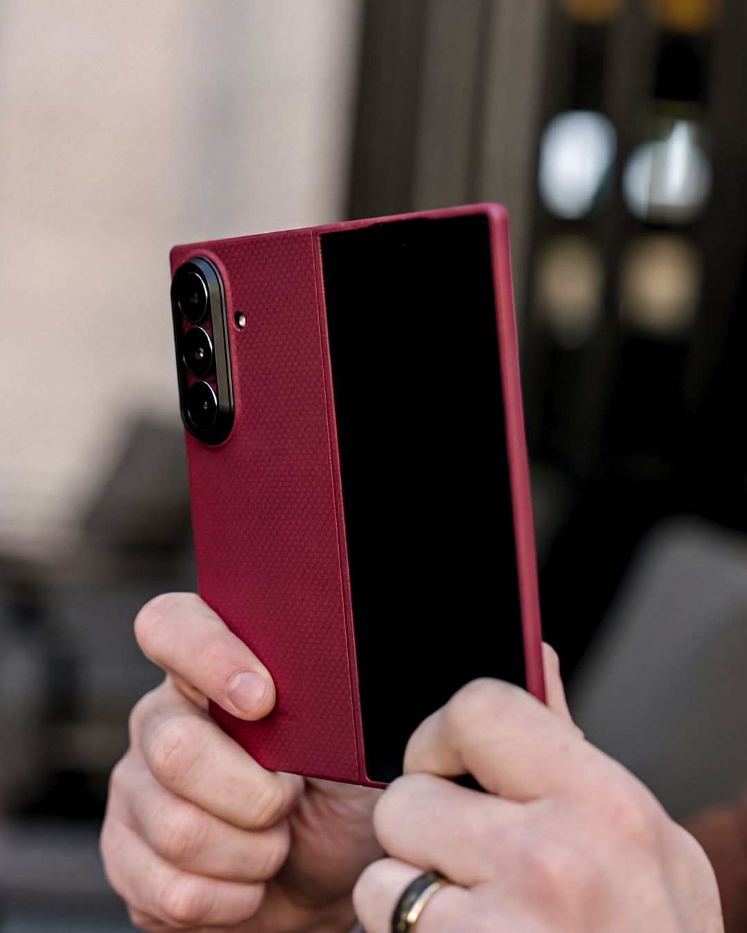 Person holding a red galaxy z fold 7 case with a blurred background