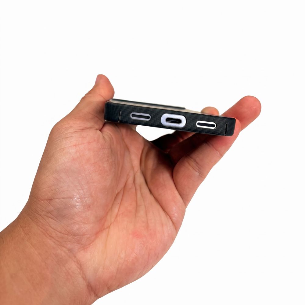 A hand holding a slim black google pixel 11 case from the bottom edge, showing port cutouts, against a plain white background.