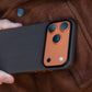 iphone 17 pro max case with carbon fiber texture and orange accents held against a brown jacket.
