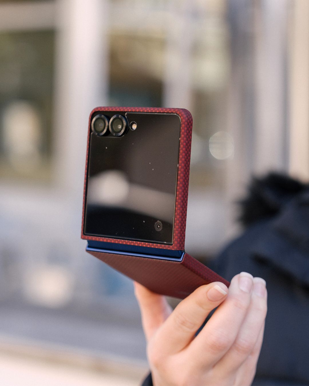 Person holding a red samsung galaxy z flip 7 phone case with a blurred background