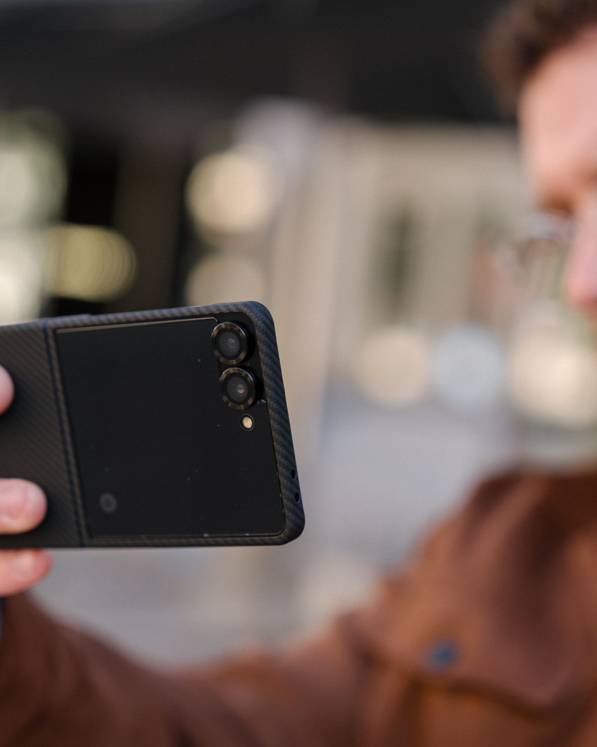 Person holding a black galaxy z flip 7 case on the phone with a blurred background