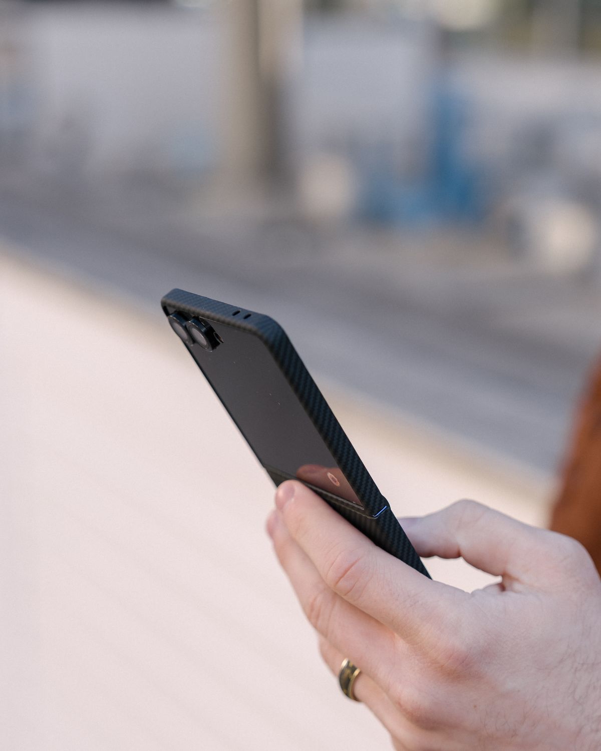 Person holding a black galaxy z flip 7 phone case outdoors