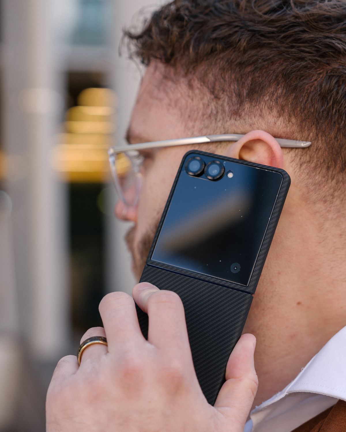 Man holding a black galaxy z flip 7 case on the phone  to his ear with a blurred background