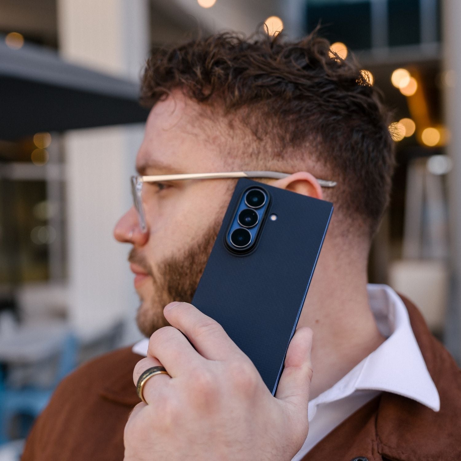A man holding a Samsung Galaxy Z Fold 8 Ultra in a navy blue aramid fiber case up to his ear as if on a call.