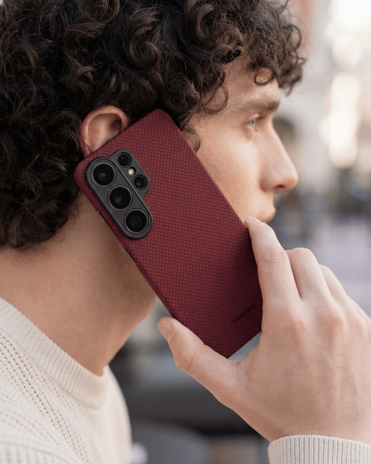 Person holding a red galaxy s26 ultra phone case with blurred background