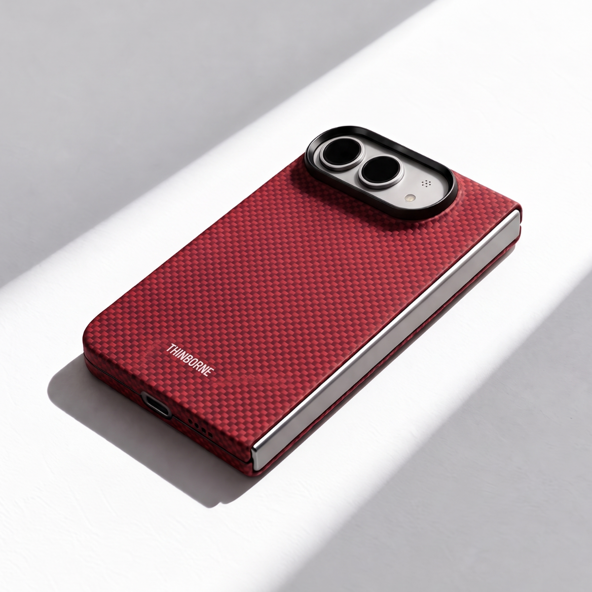 A red carbon fiber iphone duo phone case with a carbon-fiber pattern and a black camera bezel, shown on a white surface with diagonal shadows. The brand name 'TRANSFORME' is printed in white near the bottom left.
