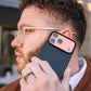 a man holding iphone 17 pro max with aramid fiber case near his ear