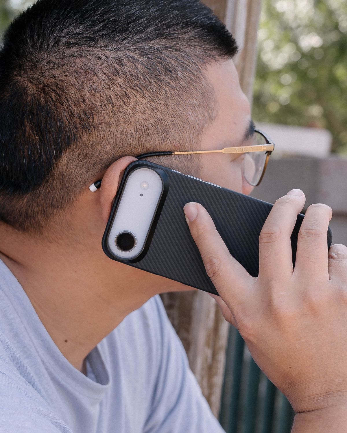 A man holds an iPhone in a carbon-fiber textured case to his ear.

