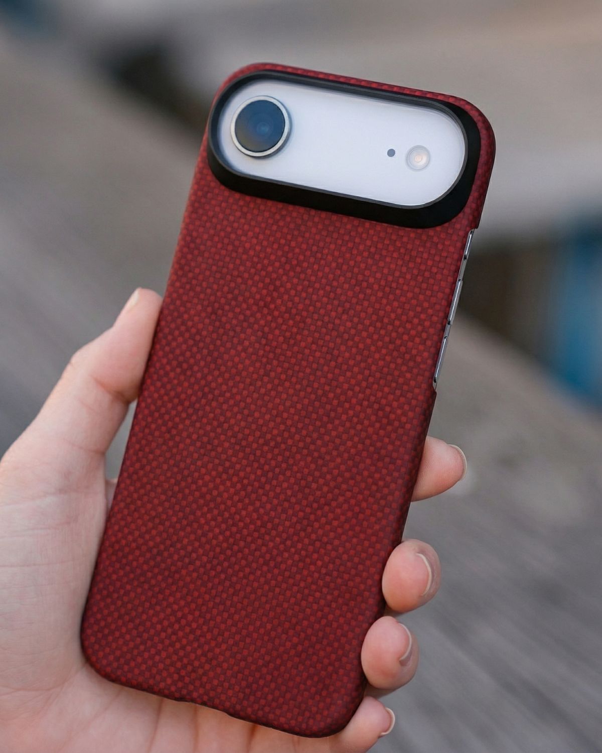 Red textured iphone air case held in a hand with a blurred background
