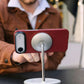 Person holding a smartphone with a iphone air case attached to a magsafe stand