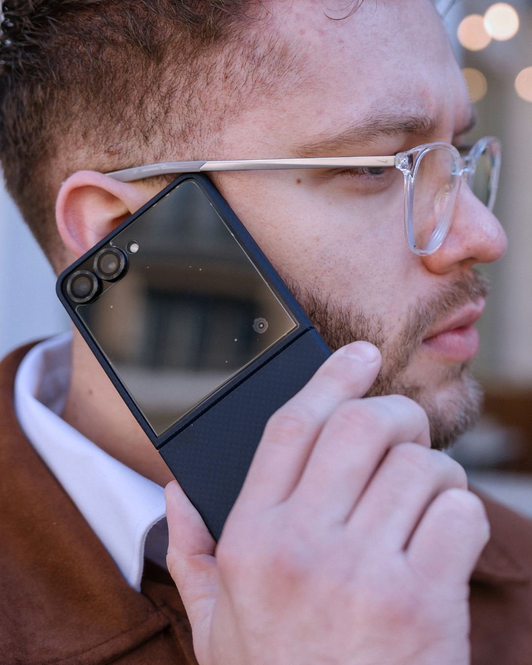 galaxy z flip 7 with aramid fiber case held by a man, near his hear