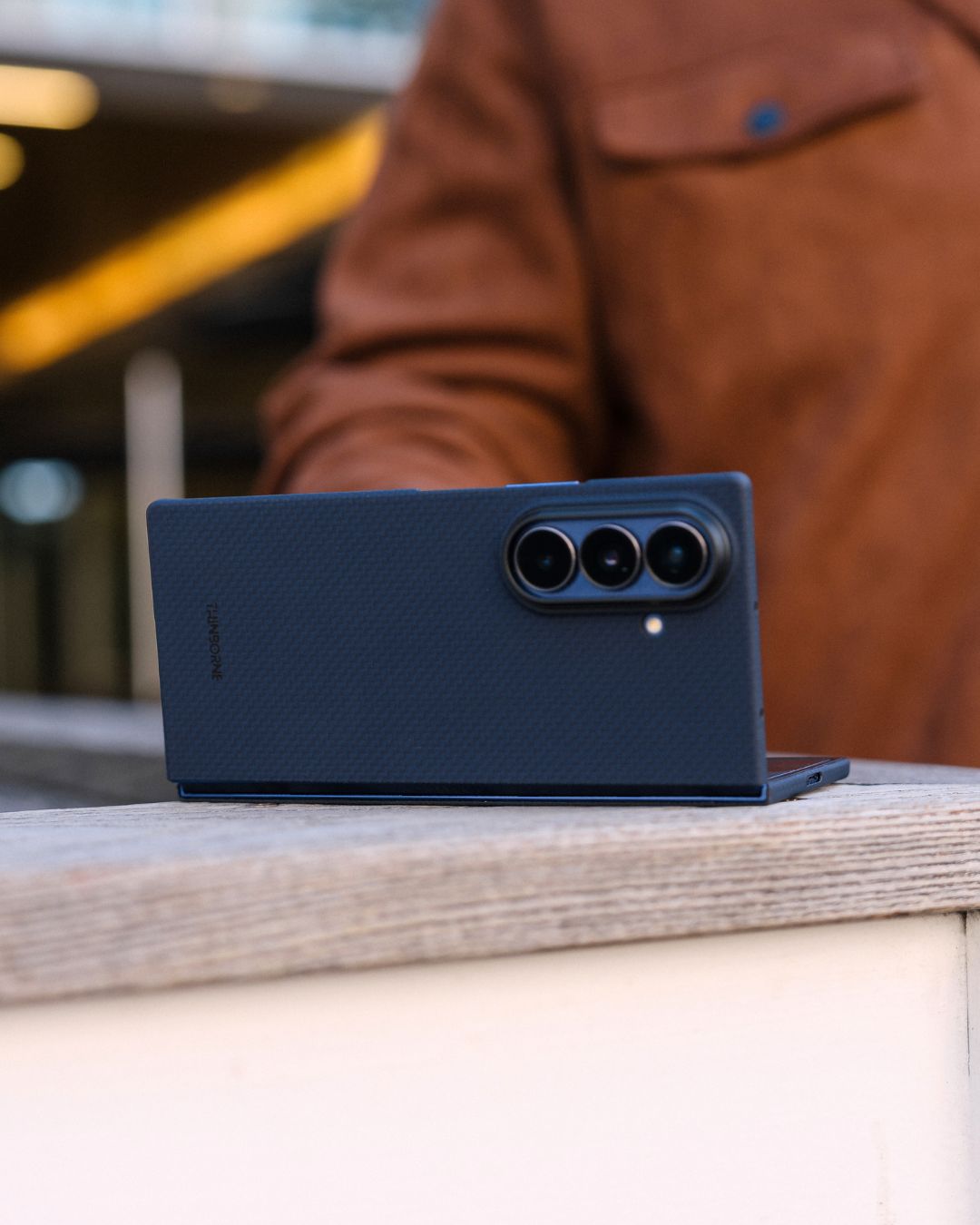 Smartphone with a carbon fiber texture galaxy z fold 7 case on a wooden surface, blurred background