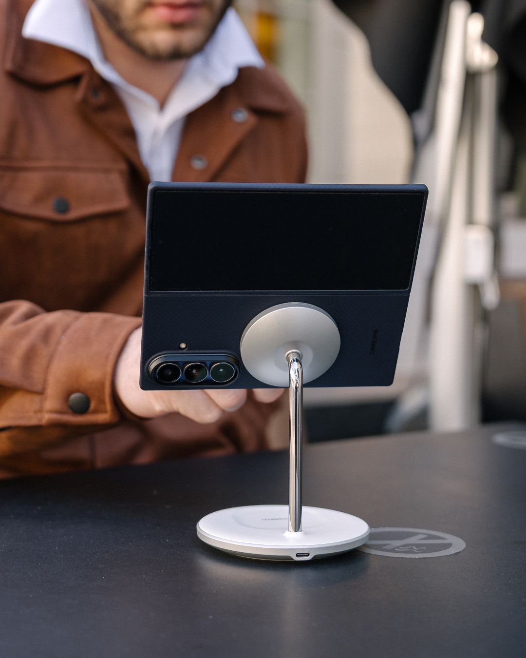 Person holding a smartphone with galaxy z fold 7 case attached to magsafe stand on a table