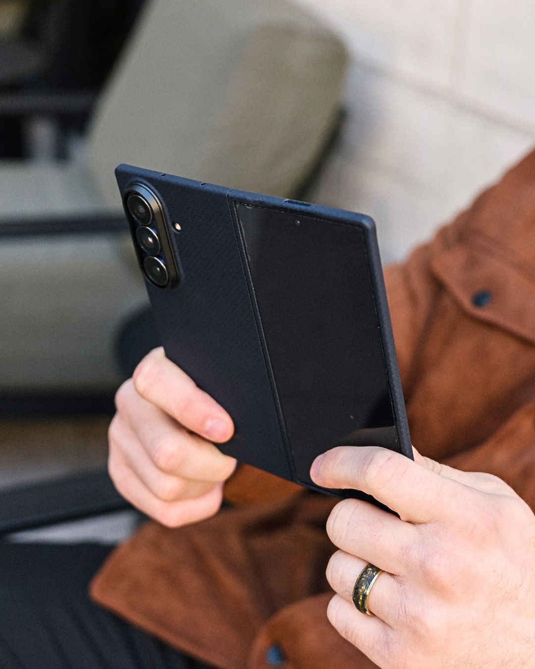 Person holding a navy galaxy z fold 7 case with a blurred background