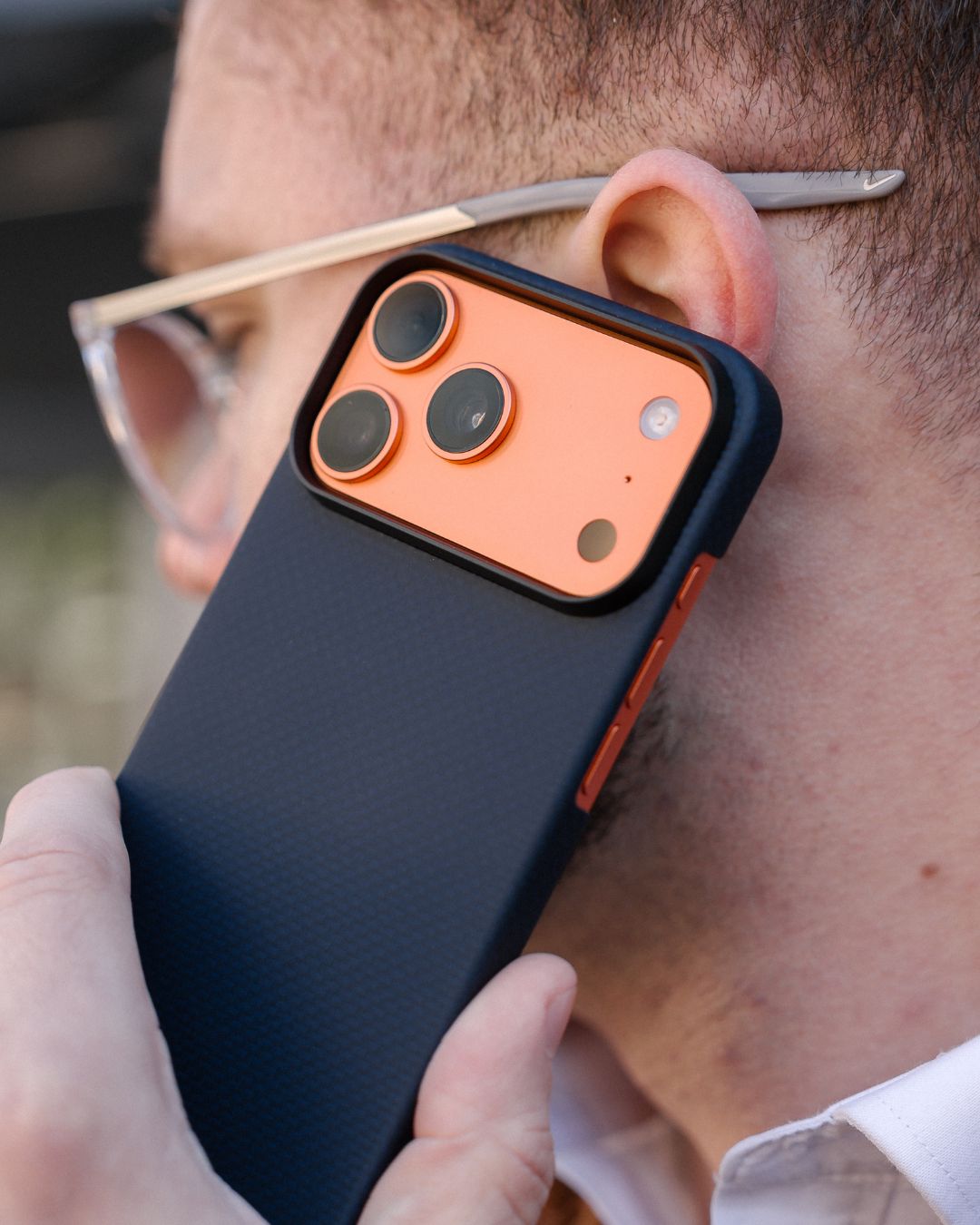Person holding a phone with an iPhone 17 pro max case close to the ear.