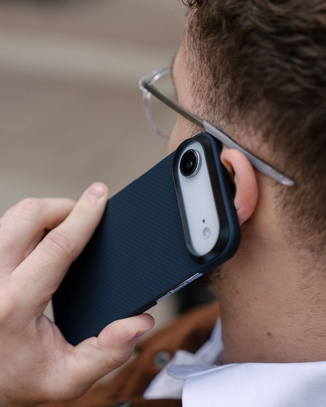 Person holding a phone with navy iphone air case to the ear with a blurred background