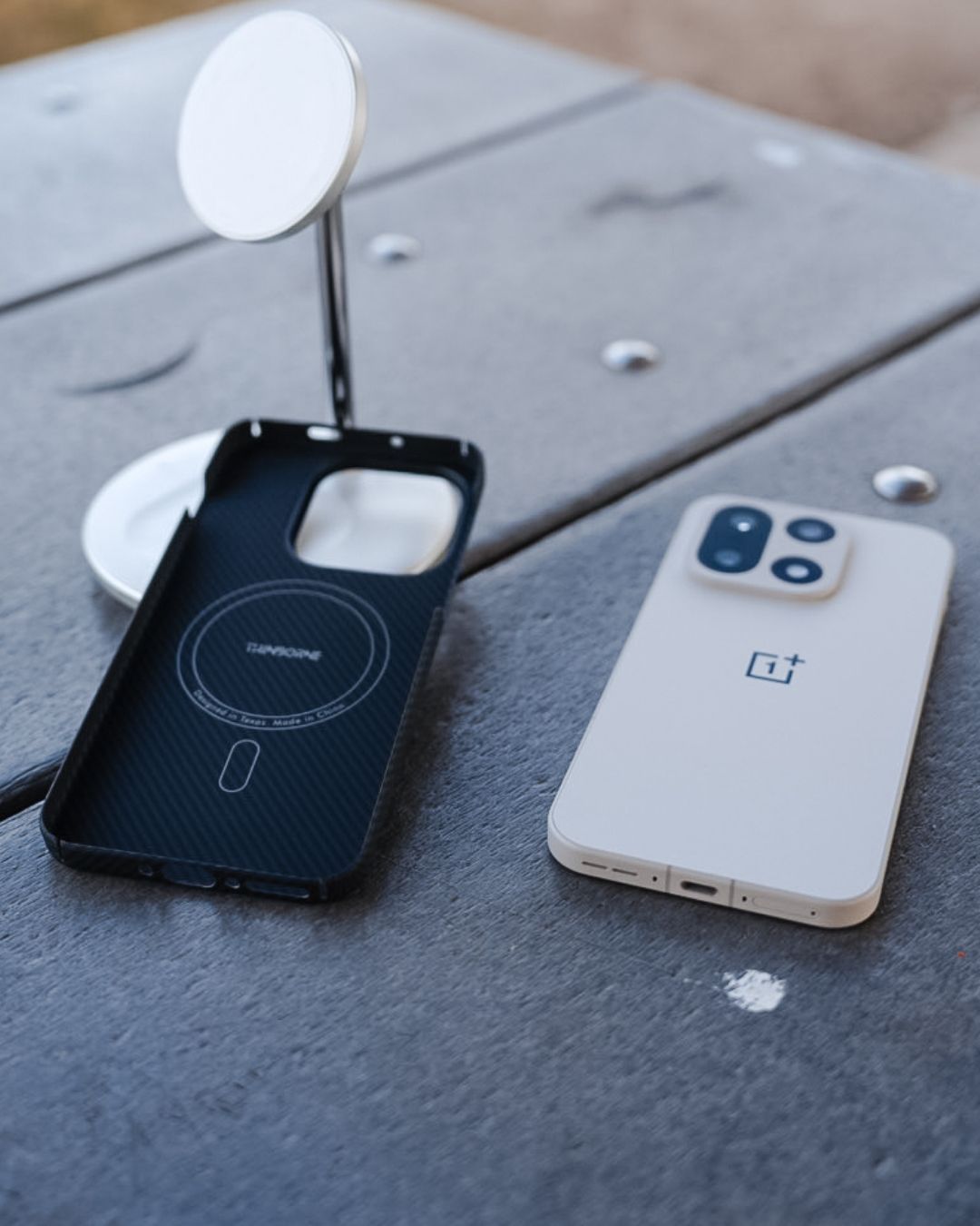 The OnePlus 15 (white model) lying next to its Thinborne aramid fiber case. The interior of the case is visible, showing the built-in MagSafe-compatible magnetic ring and the 