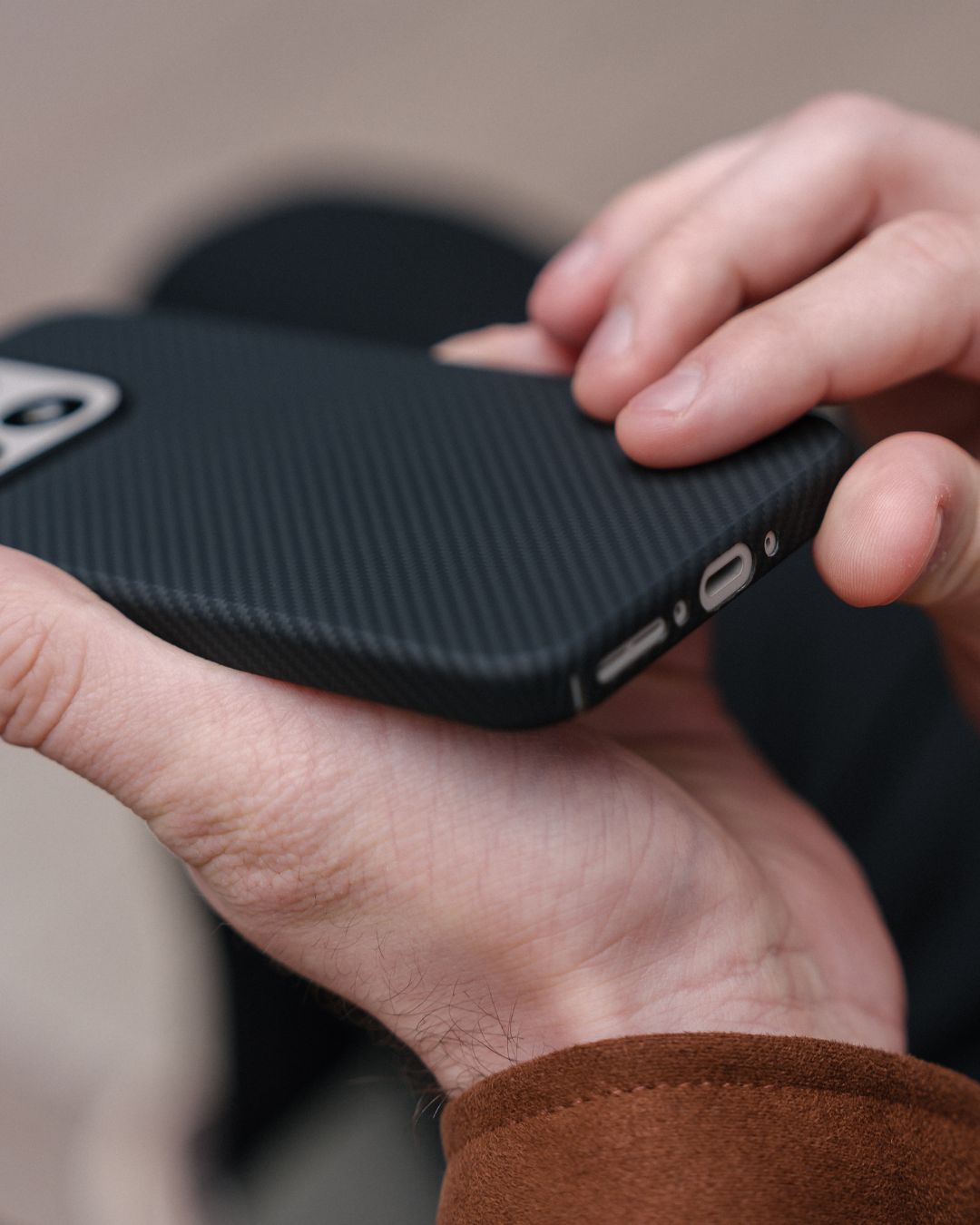 Macro view of the bottom ports and speaker cutouts on a slim-fit black OnePlus 15 case with a non-slip textured grip.