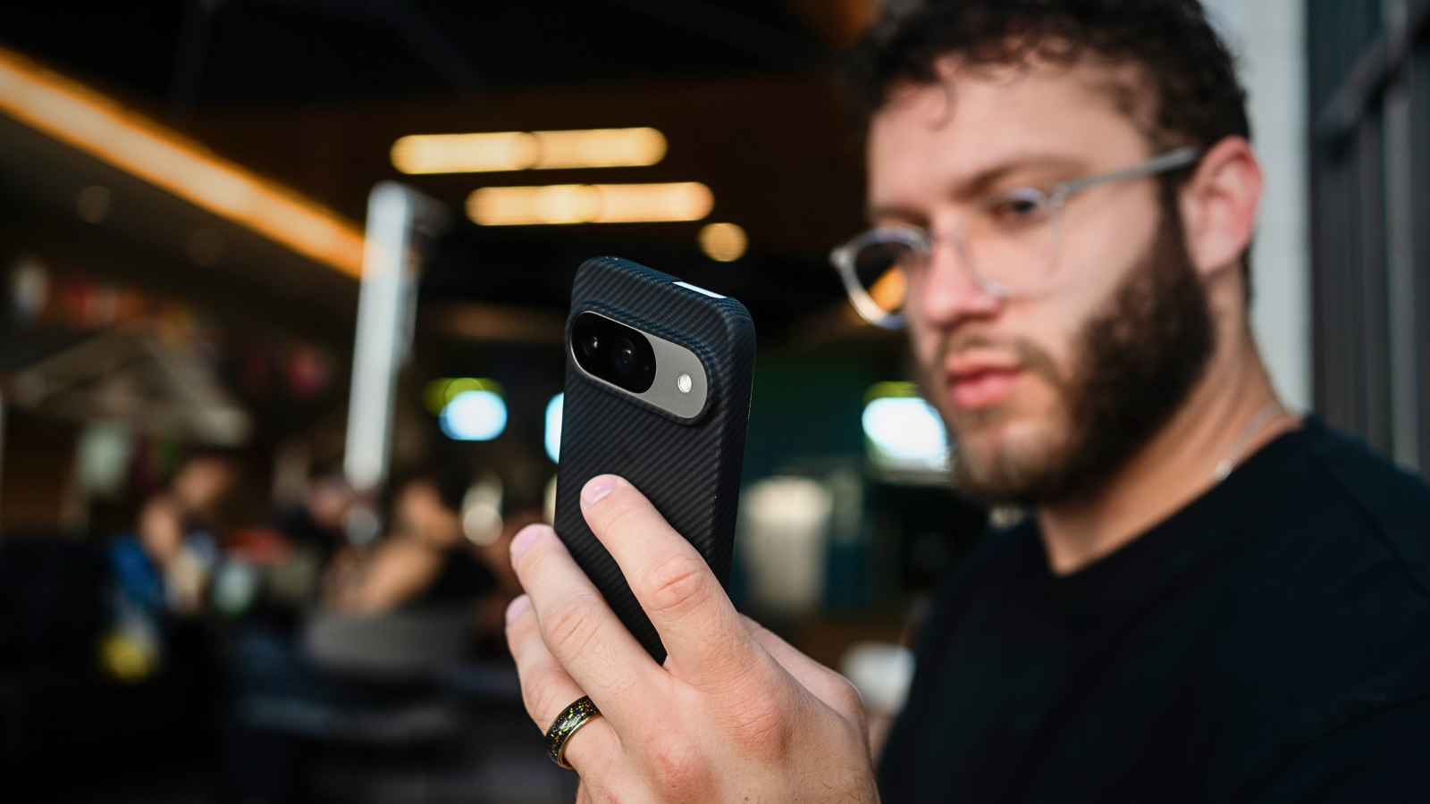 Young man holding a Pixel 9 Pro with a carbon fiber case, taking pictures.