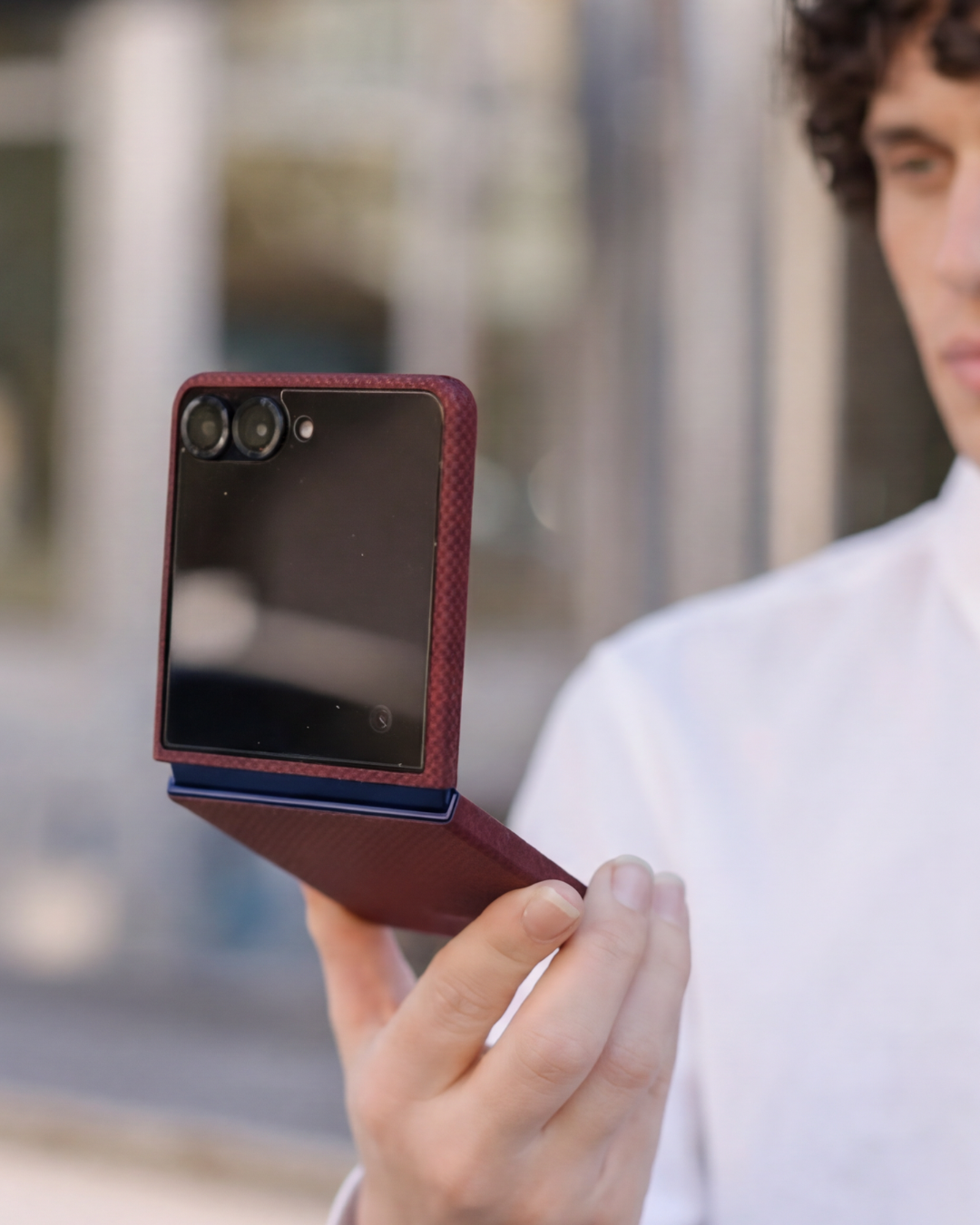 Person holding a red samsung galaxy z flip 7 phone case with a blurred background