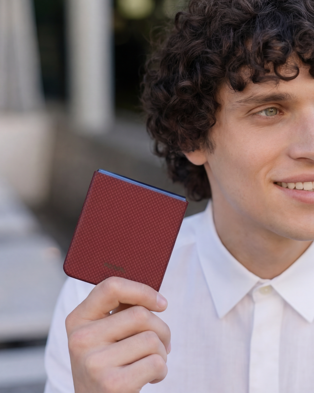 Man holding a red galaxy z flip 7 case with a blurred background