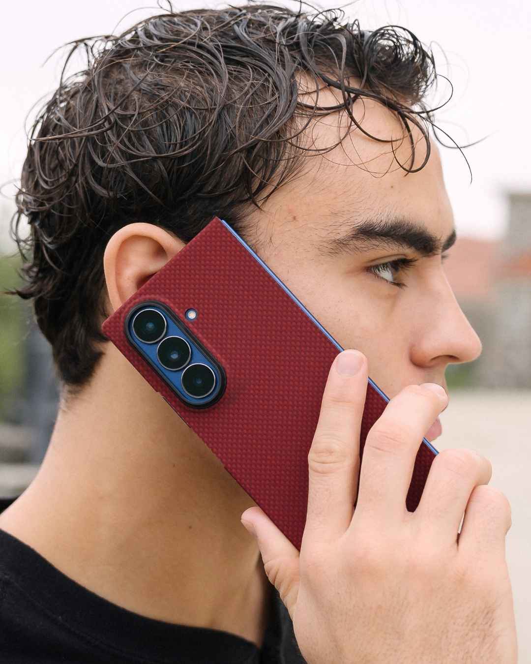 a man hold galaxy z fold 7 with aramid fiber case near his ear