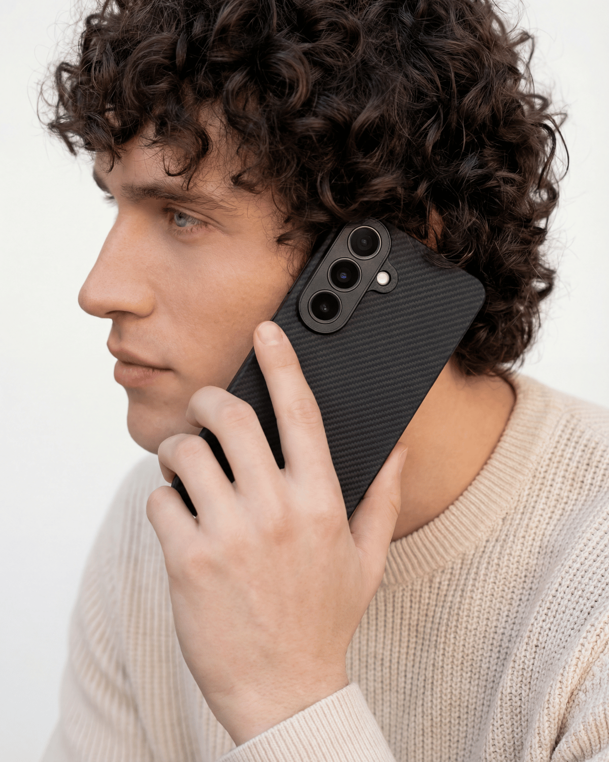 Man holding a black phone with a textured galaxy s26 case against a plain background