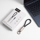 A mini PS/1 fast charging function cable with a black loop and silver metal connector, shown next to its white product packaging box and a dark laptop keyboard on a white surface.