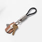 A black cable keychain with a silver metal connector and ring, holding a brown leather key fob and two keys, photographed on a clean white background.