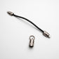 A black braided cable with silver metal connectors, shown on a clean white background alongside a small silver ring-shaped hardware piece.