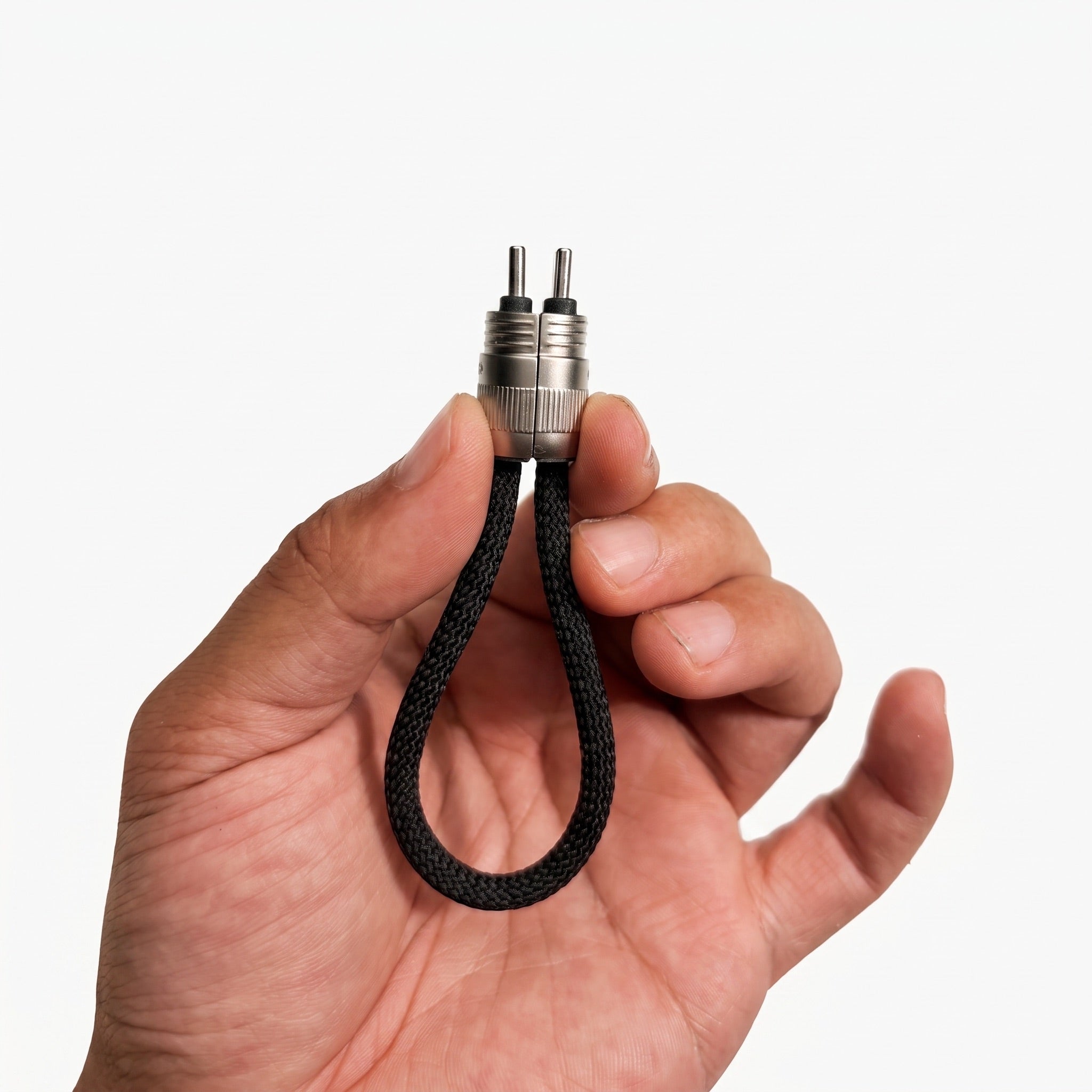 A hand holding a small black braided loop keychain with a silver metal connector and two pins, shown against a plain light gray background.
